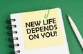 On a green surface, a pen, a notepad with stickers and the inscription - NEW LIFE DEPENDS ON YOU Royalty Free Stock Photo