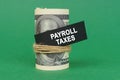 On a green surface, rolled dollars with a black sign that says - payroll taxes