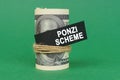 On a green surface, rolled dollars with a black sign that says - PONZI SCHEME