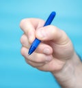 Business concept hand of man with blue pen. Close-up Studio shot of a man holding a pen with his fingers for writing on a blue Royalty Free Stock Photo