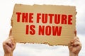 In the hands of a man is a cardboard sign with the inscription - THE FUTURE IS NOW Royalty Free Stock Photo