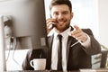 Business concept. Happy smiling young businessman sitting in office talking on a cell phone getting good news about his Royalty Free Stock Photo