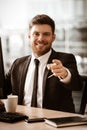 Business concept. Happy smiling young businessman sitting in office, working on computer and pointing with finger. Man Royalty Free Stock Photo