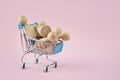 Business concept. Lamp with wooden people in a shopping cart on a pink background. Employment, selection of people. Business ideas