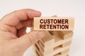 A man holds in his hands a wooden block with the inscription - Customer Retention