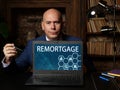 Business concept meaning REMORTGAGE with sign on the laptop. The process of paying off one mortgage with the proceeds from a new