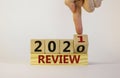 Business concept of new year 2021 review. Male hand flips wooden cube and changes the inscription `Review 2020` to `Review 2021