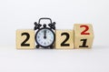 Business concept of 2022 new year. Turned a wooden cube and changed number 2021 to 2022. Black alarm clock. Beautiful white