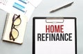 Business concept. Notebook with text Home refinance sheet of white paper for notes, glasses in the white background Royalty Free Stock Photo