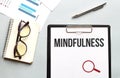 Business concept. Notebook with text MINDFULNESS sheet of white paper for notes, glasses in the white background