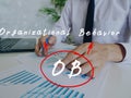 Business concept about OB Organizational Behavior with handwritten acronym.Busy businessman under stress due to excessive work on