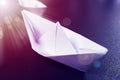 Business concept. paper ship is heading for success. White origami boat on black background with sunlight flare Royalty Free Stock Photo