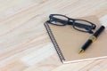 Business concept, pen, glasses and notebook on wooden office tab Royalty Free Stock Photo