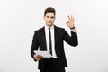 Business Concept: Portrait attractive businessman working on report and showing ok finger sign. over grey copy Royalty Free Stock Photo