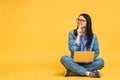 Business concept. Portrait of happy young woman in casual sitting on floor in lotus pose and holding laptop isolated over yellow Royalty Free Stock Photo