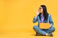 Business concept. Portrait of happy young woman in casual sitting on floor in lotus pose and holding laptop isolated over yellow Royalty Free Stock Photo