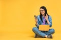 Business concept. Portrait of happy young woman in casual sitting on floor in lotus pose and holding laptop isolated over yellow Royalty Free Stock Photo