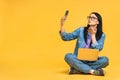 Business concept. Portrait of happy young woman in casual sitting on floor in lotus pose and holding laptop isolated over yellow Royalty Free Stock Photo