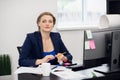 Business concept. A portrait of a smiling young attractive business woman sitting at her desk looking at the camera Royalty Free Stock Photo