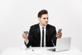 Business Concept: Portrait of young businessman using laptop computer and mobile phone holding debit card. Isolated over Royalty Free Stock Photo