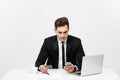 Business Concept: Portrait of young businessman using laptop computer and mobile phone holding debit card. Isolated over Royalty Free Stock Photo