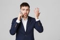 Business Concept - Portrait young handsome angry business man in suit talking on phone looking at camera. White background. Royalty Free Stock Photo