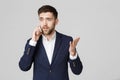 Business Concept - Portrait young handsome angry business man in suit talking on phone looking at camera. White background. Royalty Free Stock Photo