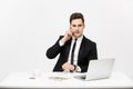 Business Concept: Portrait young successful businessman working in bright office, using laptop, talking on phone. Royalty Free Stock Photo