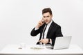 Business Concept: Portrait young successful businessman working in bright office, using laptop, talking on phone. Royalty Free Stock Photo