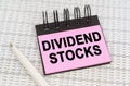 On reporting documents and charts there is a pen and a notepad with the inscription - Dividend stocks Royalty Free Stock Photo