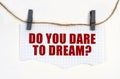 A sheet of paper with the inscription is attached to the rope with clothespins - DO YOU DARE TO DREAM