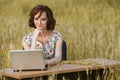 Business concept shot of a beautiful young woman sitting at a desk using a computer in a field. Royalty Free Stock Photo