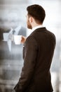 Business concept. Successful young businessman back at work. Manager standing in office happy drinking coffee from cup Royalty Free Stock Photo