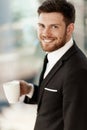 Business concept. Successful young businessman at work. Manager standing in office happy drinking coffee from cup. Man Royalty Free Stock Photo