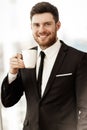 Business concept. Successful young businessman at work. Manager standing in office happy drinking coffee from cup. Man Royalty Free Stock Photo