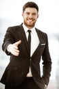 Business concept. Successful young businessman at work. Manager standing in office happy reaches out for a handshake Royalty Free Stock Photo