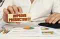 On the table are business charts and diagrams in the hands of a wooden block with the inscription - Improve Productivity