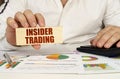 On the table are business charts and diagrams in the hands of a wooden block with the inscription - insider trading