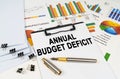 On the table among financial graphs and charts lies a tablet with the inscription - annual budget deficit Royalty Free Stock Photo