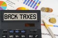 On the table are financial reports, coins and a calculator with the inscription - BACK TAXES Royalty Free Stock Photo