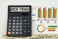 On the table are financial reports, dollars and a calculator with the inscription - BACK TAXES Royalty Free Stock Photo