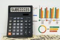 On the table are financial reports, dollars and a calculator with the inscription - Subsidies Royalty Free Stock Photo