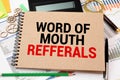 Word Of Mouth Referrals inscription in notebook, calculator and abacus