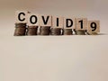 Business Concept - text COVID19 written on wooden blocks with downward stack of coins background. Stock photo. Royalty Free Stock Photo