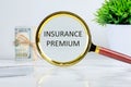Business concept. text INSURANCE PREMIUM written through a magnifying glass on a light background near a roll of money and a pot Royalty Free Stock Photo