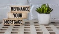 Business concept. Text REFINANCING YOUR MORTGAGE on wooden blocks and beautiful background with cactus