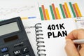 There is a calculator on the table, business charts, a man made a note in a notebook - 401K PLAN