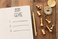 Business concept of top view 2020 goals list with notebook, chess figures and compass over wooden desk Royalty Free Stock Photo