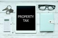 Business concept, Top view of home key,calculator,pen,glasses,notebook and tablet pc written with Property Tax. Royalty Free Stock Photo