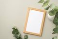 Business concept. Top view photo of wooden photo frame and white ceramic vase with bouquet of eucalyptus on pastel grey background